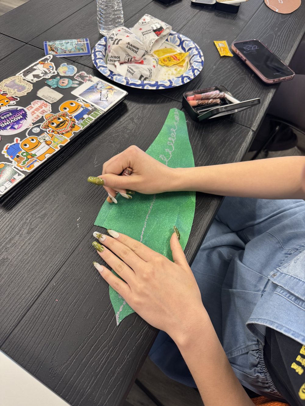 Hands painting a leaf shaped piece