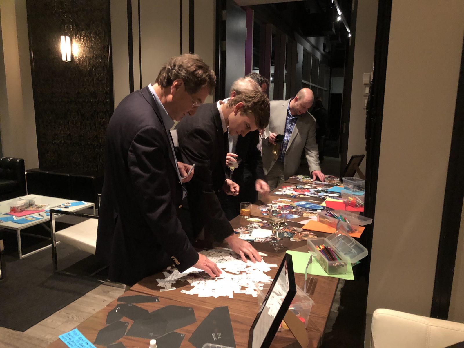 Guests in suits building collages along a long table