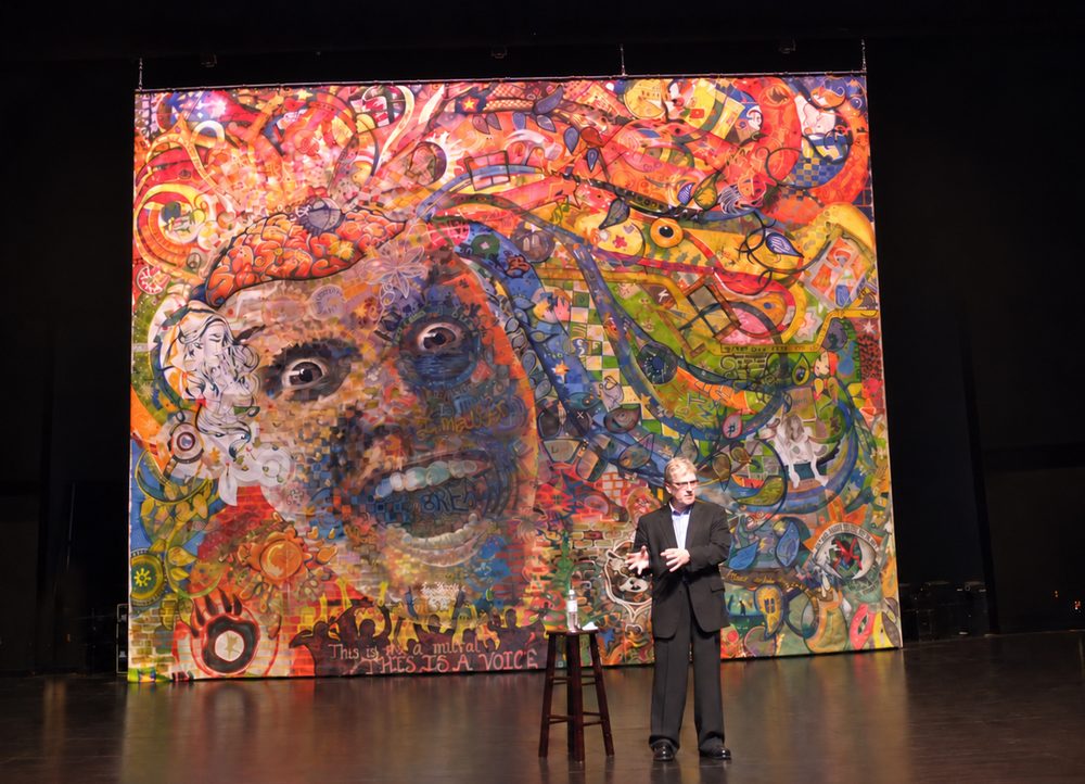 Sir Ken Robinson speaking in front of the students&rsquo; large painting