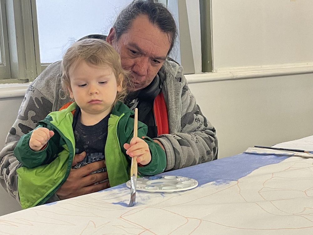 A father and toddler painting together