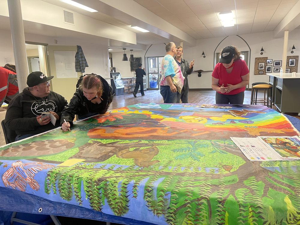 People painting a large canvas on tables