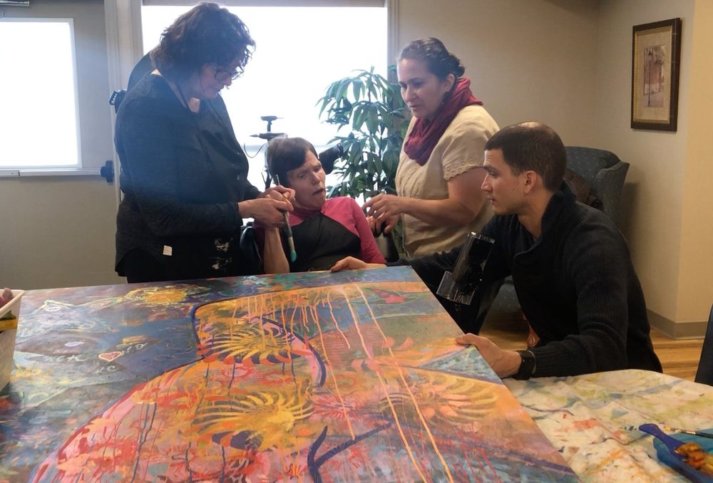 Two participants painting side by side on a shared canvas