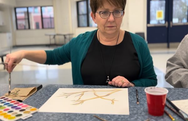 A participant painting at a cafeteria table